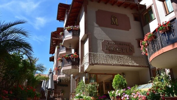 A hotel with multiple balconies adorned with flowers and potted plants. - Club Hotel Martin (Bansko)