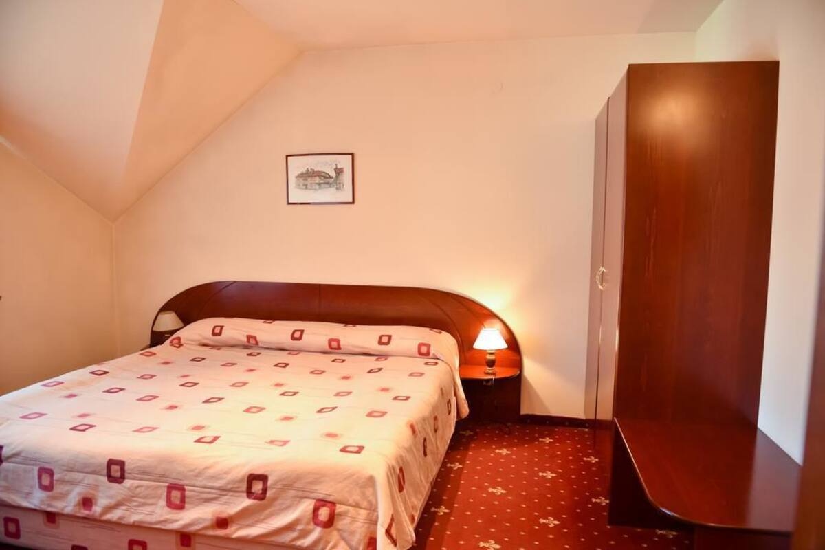 Un dormitorio con cama, mesita de noche, armario de madera y un cuadro enmarcado en la pared.