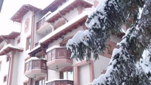 A multi-story building with balconies, snow-covered trees, and a clear sky. - Club Hotel Martin (Bansko)