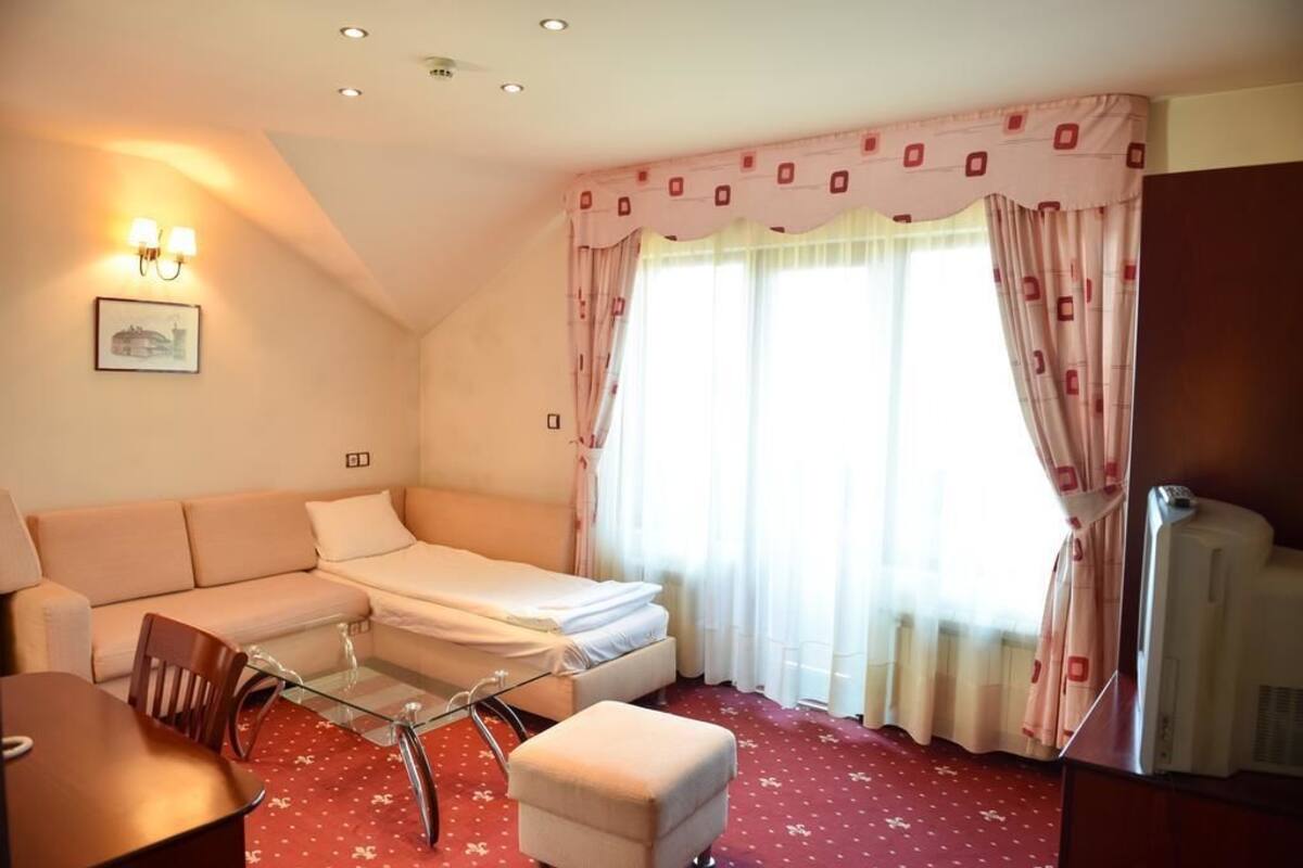 Una habitación de hotel con una cama, un sofá, una mesita de cristal, una silla y un televisor.