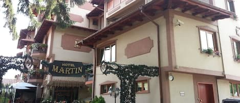 A two-story building with a sign reading "HOTEL MARTIN". There are potted plants and a small outdoor seating area.