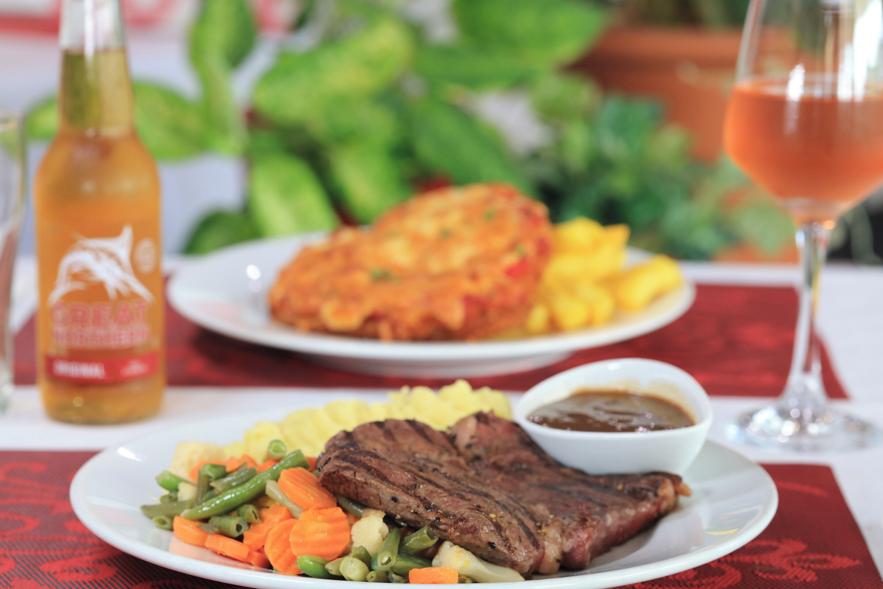 A plate of food with steak, vegetables, and a side of sauce.