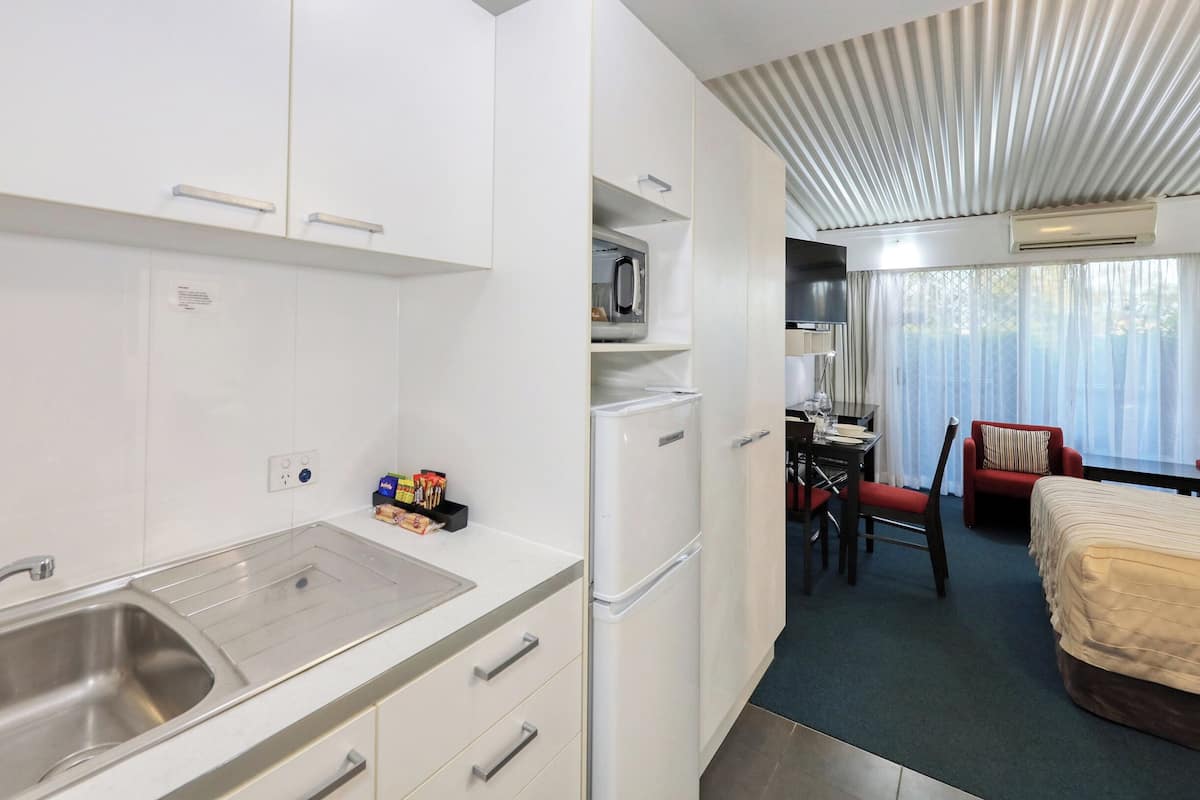 Une chambre d’hôtel compacte comprenant un coin cuisine, un espace repas et un lit.