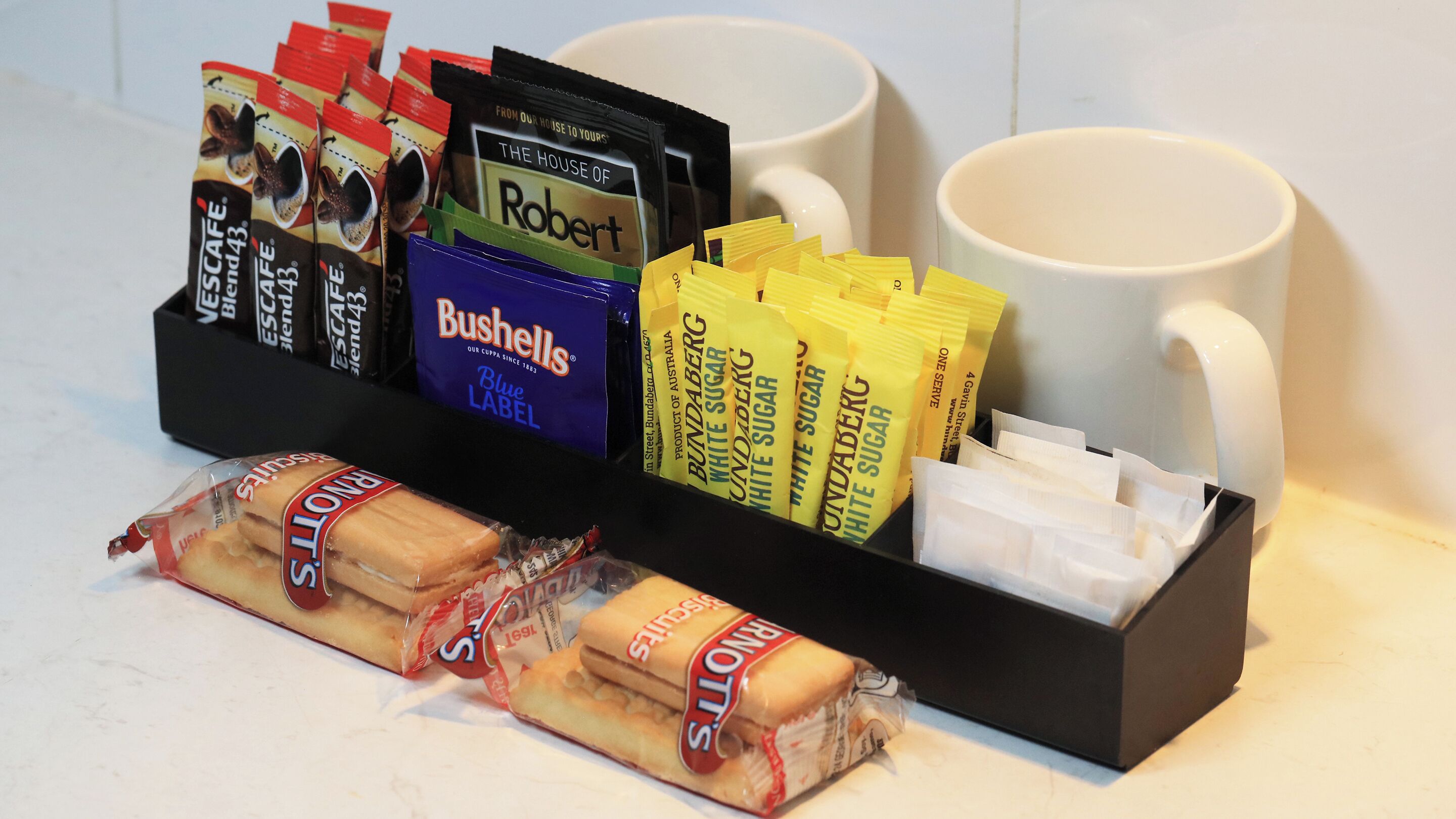 A coffee and snack station with branded items like 'Bushells' and 'Robert's' coffee, and 'Ronalys' biscuits.