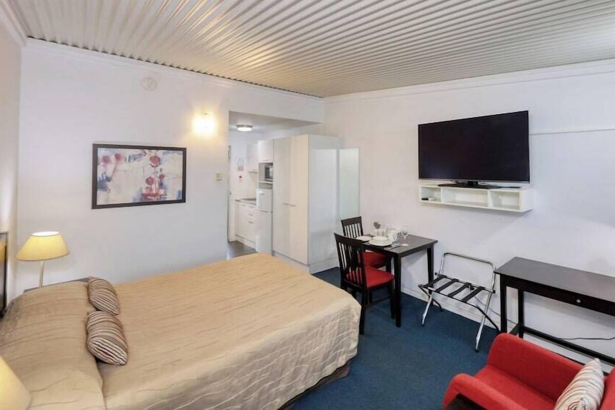 Une chambre d’hôtel avec un lit, un bureau, une chaise, une télévision et une lampe.