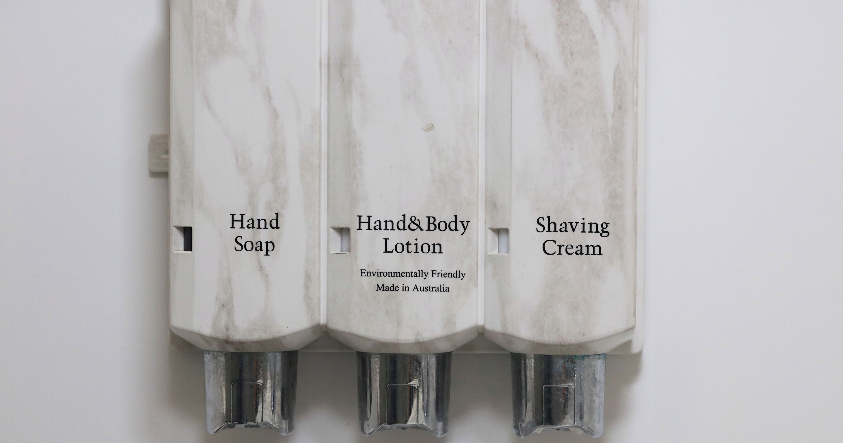 Three bottles of hand soap, hand and body lotion, and shaving cream.