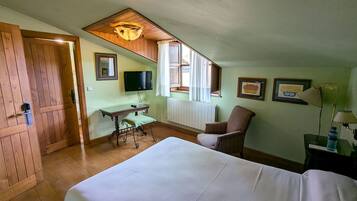 Una habitación de hotel con cama, escritorio, silla, televisor y ventana con cortinas.