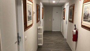 Un pasillo con cuadros en las paredes, un radiador y un extintor.