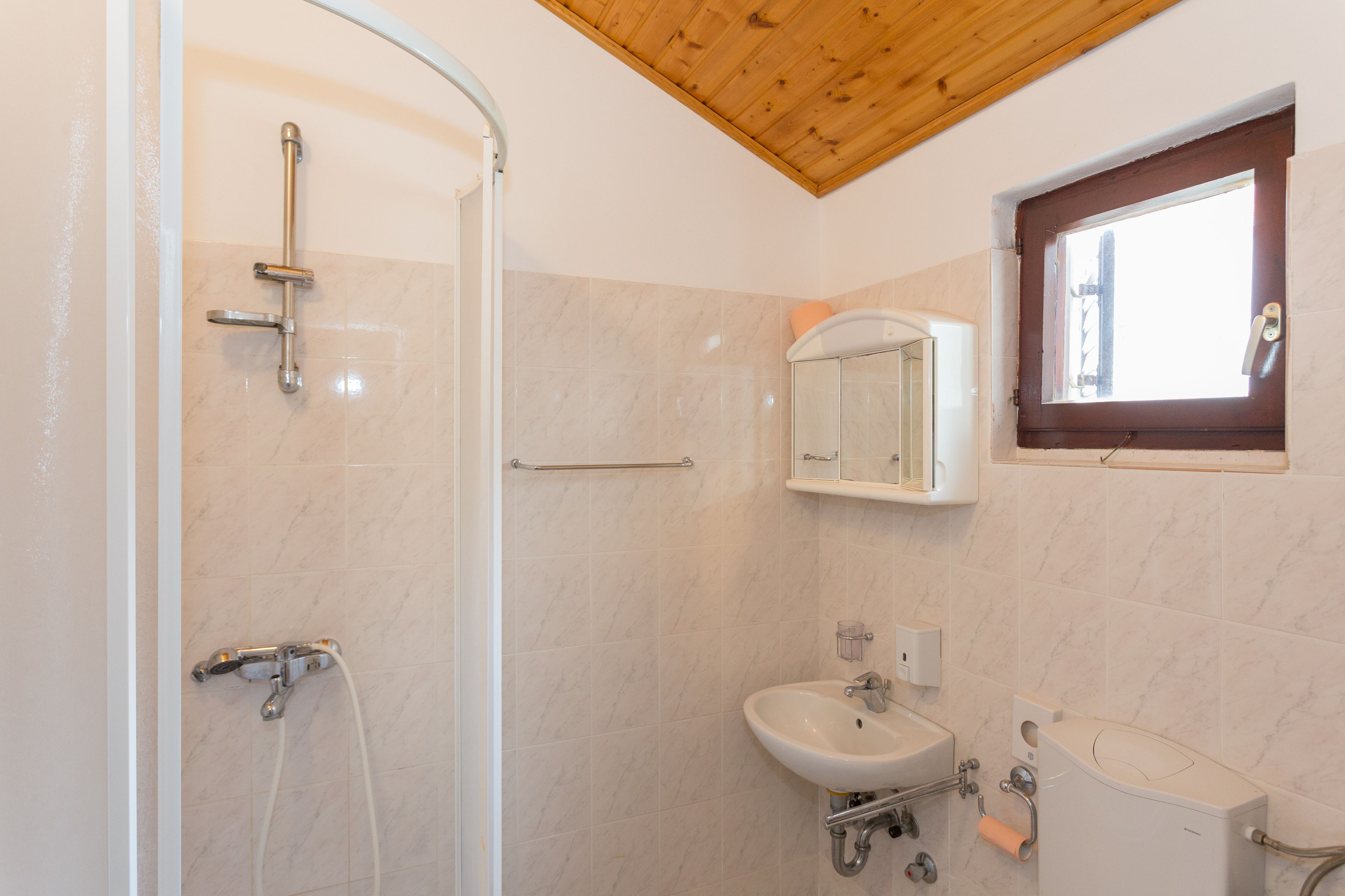 Une salle de bain avec une douche, un lavabo, des toilettes et une fenêtre.