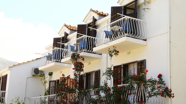 A multi-story building with balconies, some with metal railings and others with wooden shutters. - Villa Anka (Konavle)