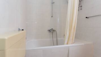 A bathroom with a bathtub, shower, and toilet.