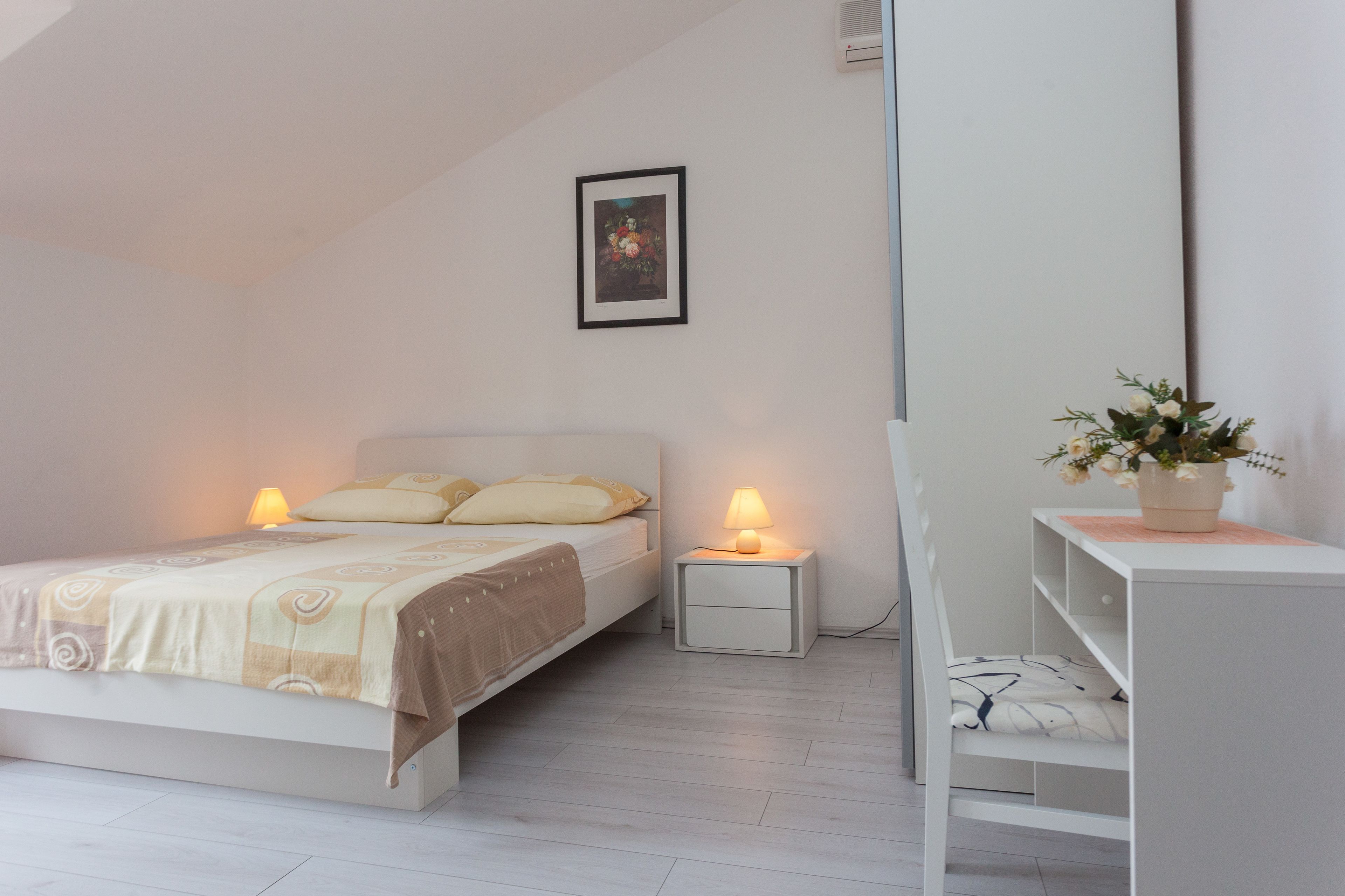 Un dormitorio con cama, mesitas de noche, un escritorio y una planta en maceta.