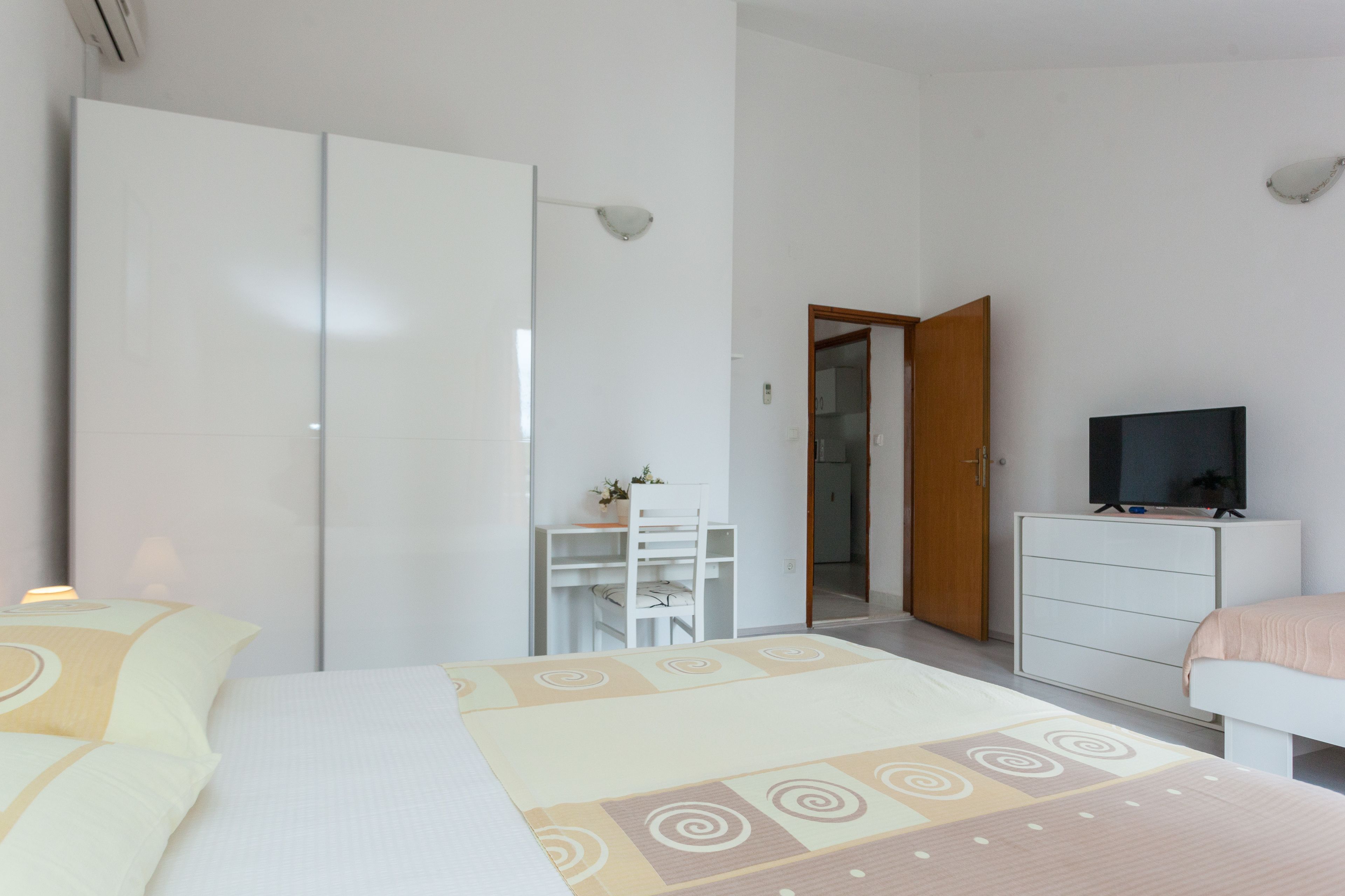 Un dormitorio con cama, escritorio, televisión y armario.