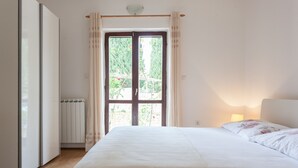 A bedroom with a bed, a radiator, and a window with curtains. - Villa Anka (Konavle)