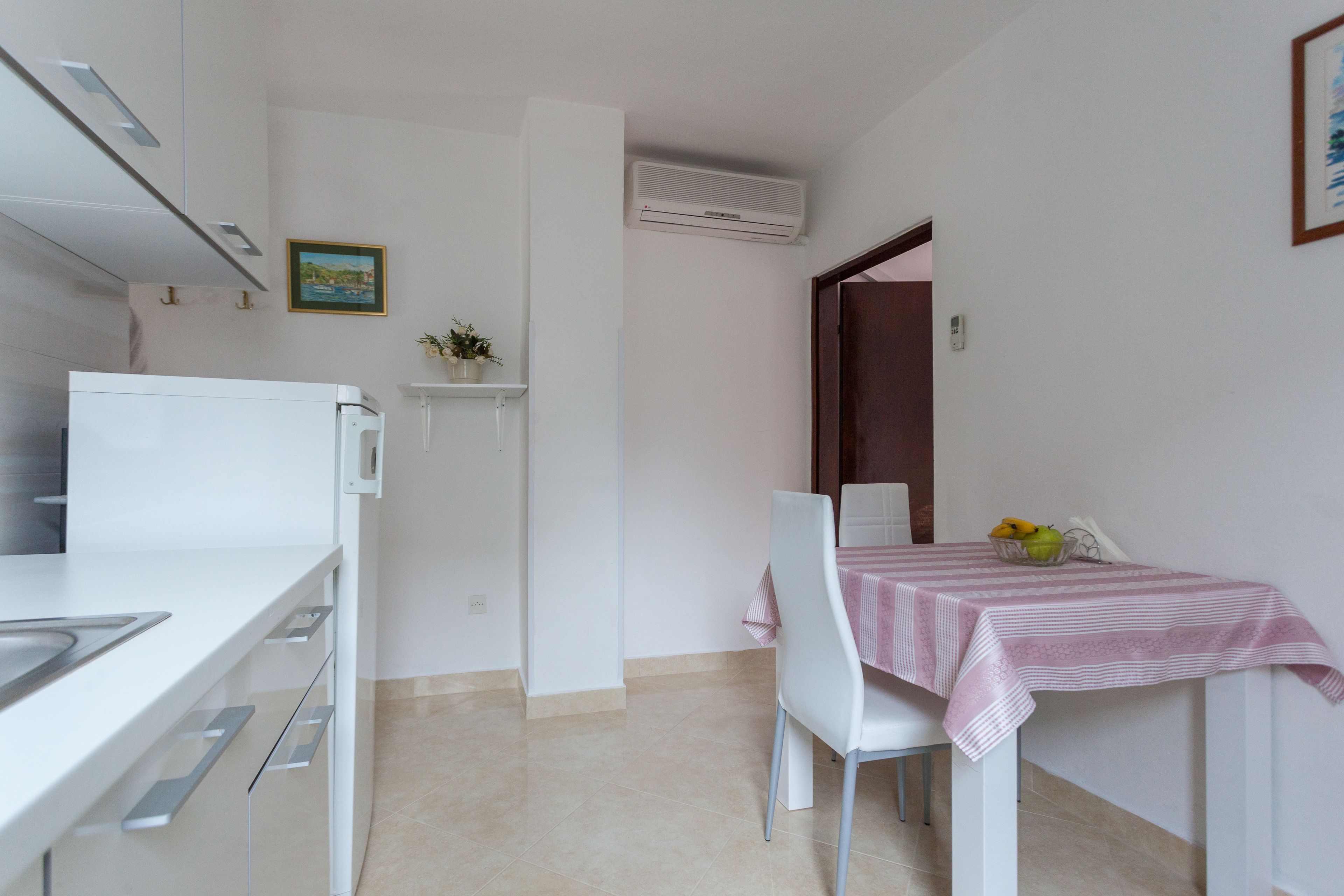 Cocina compacta con microondas, un lavamanos y un pequeño comedor con mesa y sillas.
