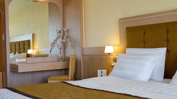 Una habitación de hotel con una cama grande, una mesita de noche, un espejo y una lámpara.
