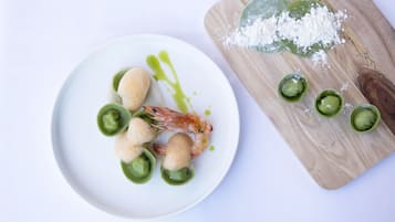A plate with shrimp and green sauce, and a wooden board with green sauce and salt.