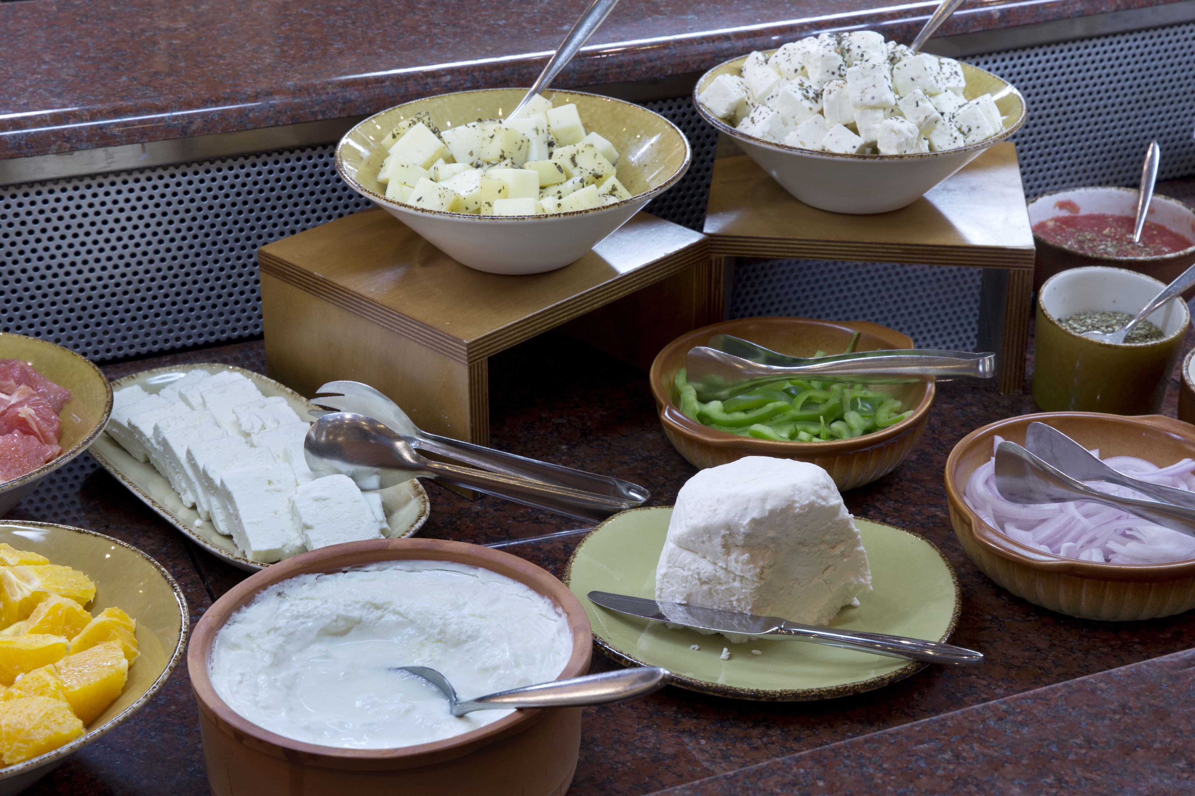 Un bufé con diversos alimentos, incluyendo queso, frutas y verduras.