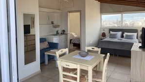 Une chambre compacte et moderne, dotée d’une kitchenette, d’un coin repas et d’un lit offrant une vue sur la ville.