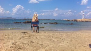 Une personne assise sur une chaise de plage, face à la mer, avec un phare en arrière-plan.