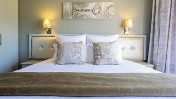 A neatly made bed with a fluffy brown throw, two bedside lamps, and a decorative wall piece above the bed.