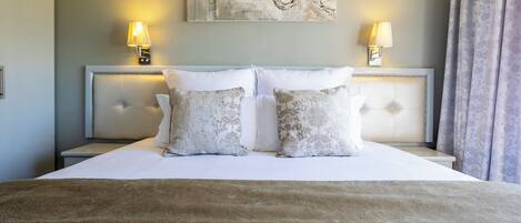 A neatly made bed with a fluffy brown throw, two bedside lamps, and a decorative wall piece above the bed.