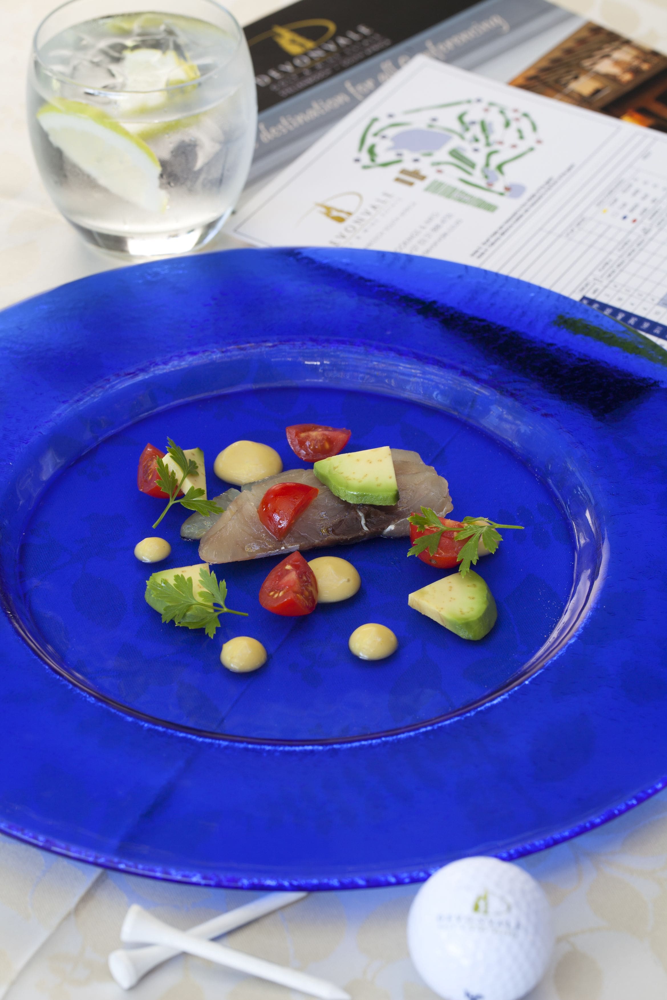 Um prato azul com prato de frutos do mar, um copo de água e um menu.