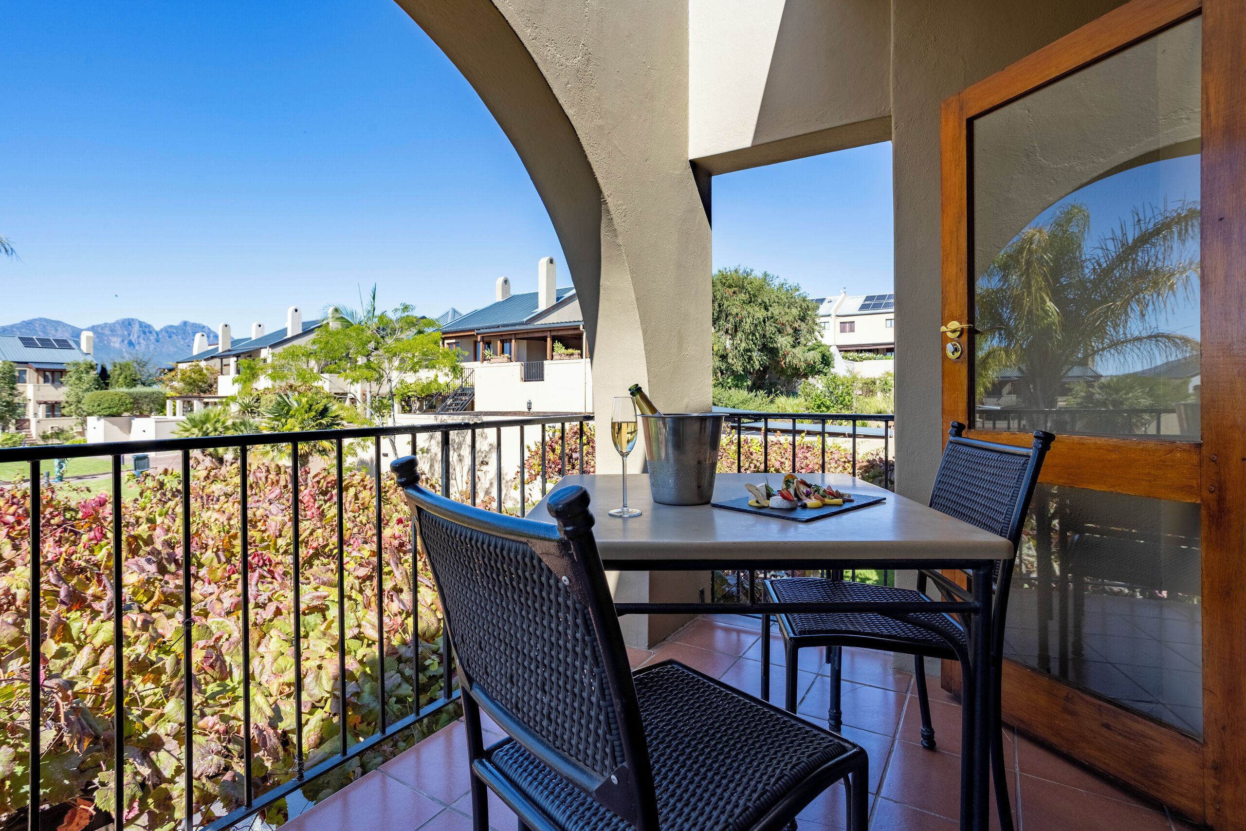 A balcony with a table, chairs, and a bottle of wine.