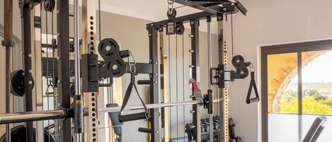 A gym with a squat rack, weight bench, and various free weights.