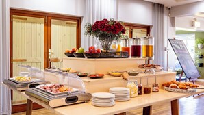 A buffet setup with various food items, a vase of red roses, and a juice station. - Devonvale Golf & Wine Estate (Stellenbosch)