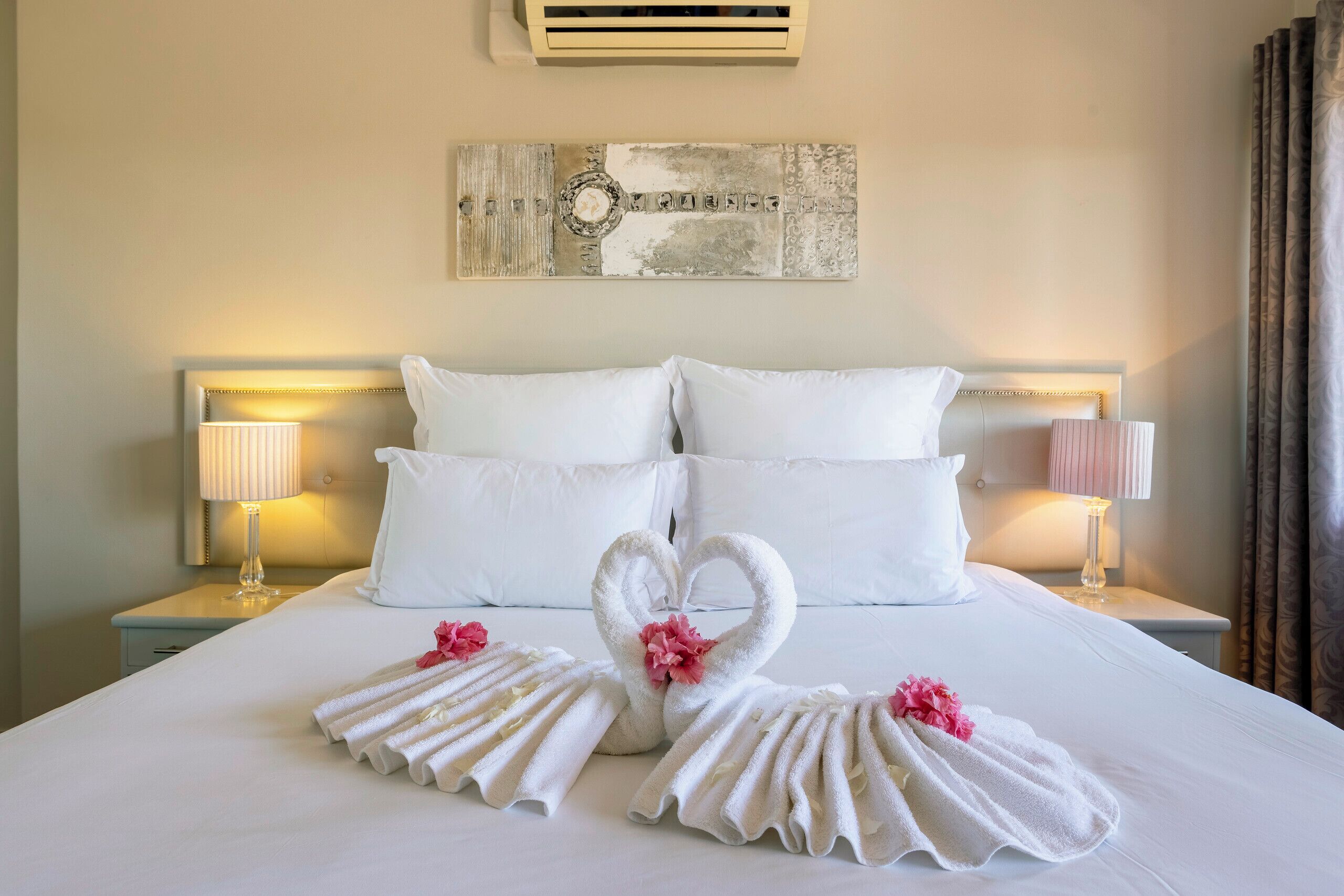 A hotel room with a large bed, two nightstands, and a wall art piece above the bed.