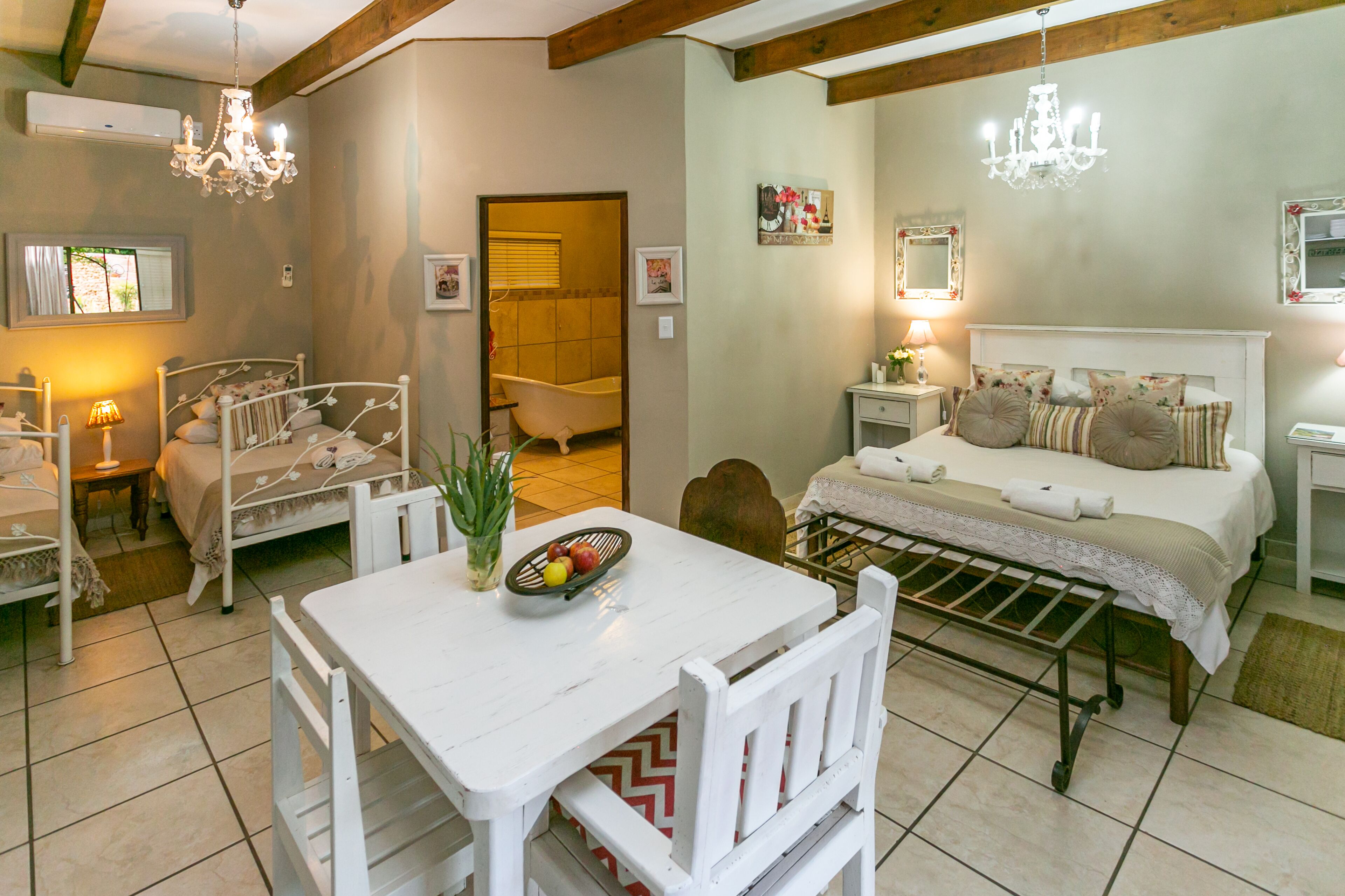 A bedroom with a bed, bedside table, lamp, and a small table with fruit.