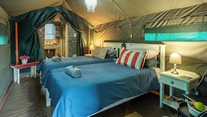 A tented room with two beds, a small table with a lamp, and a chair. - Die Fonteine Guesthouse and Glamping (Oudtshoorn)