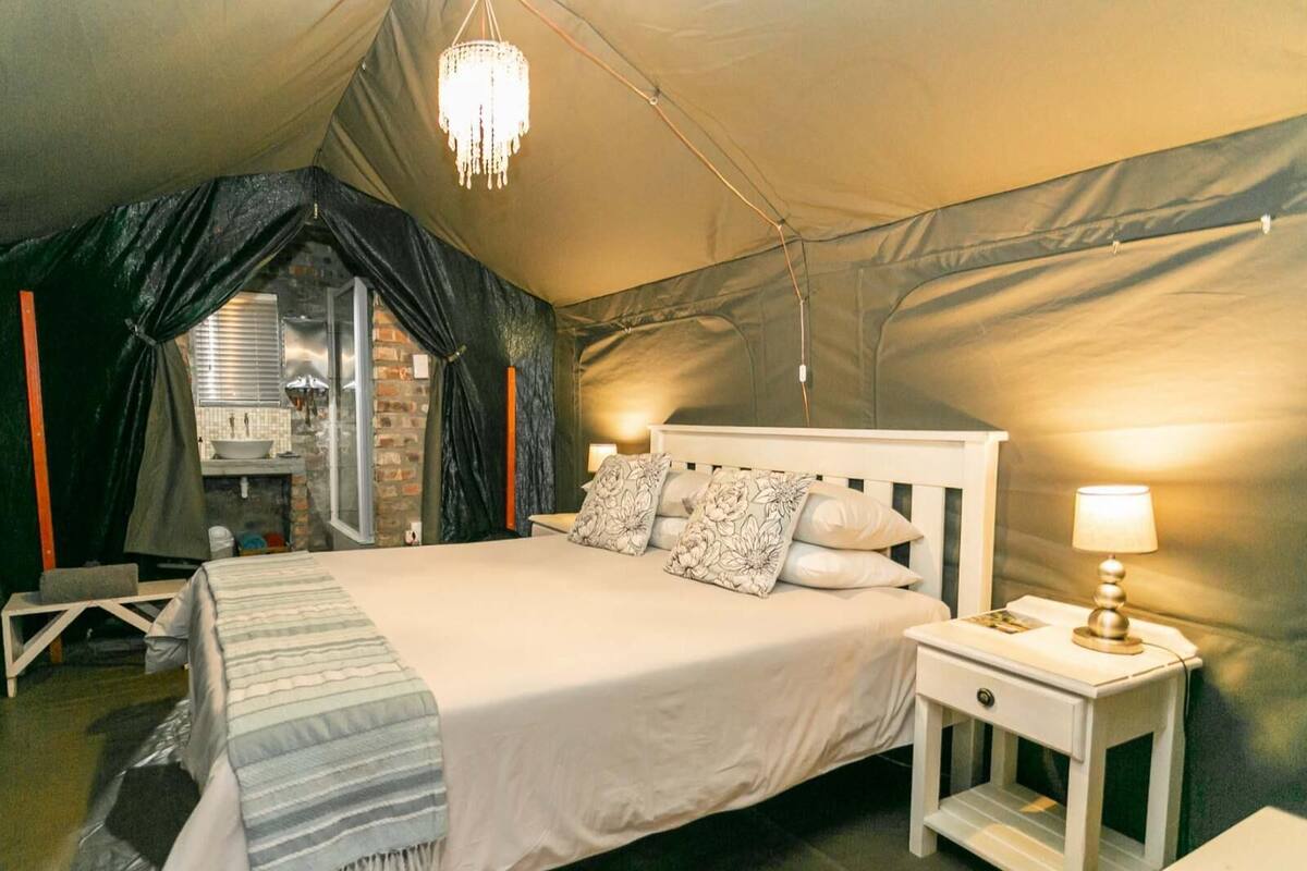 A tented room with a bed, bedside tables, and a chandelier.