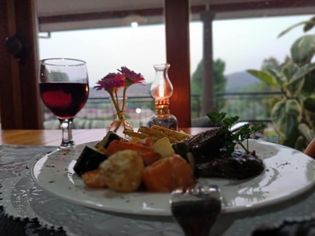 Een eettafel met een bord eten, een glas rode wijn en een kaars.