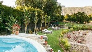 A backyard with a swimming pool, stone steps, a small garden, and a wooden fence. - Die Fonteine Guesthouse and Glamping (Oudtshoorn)