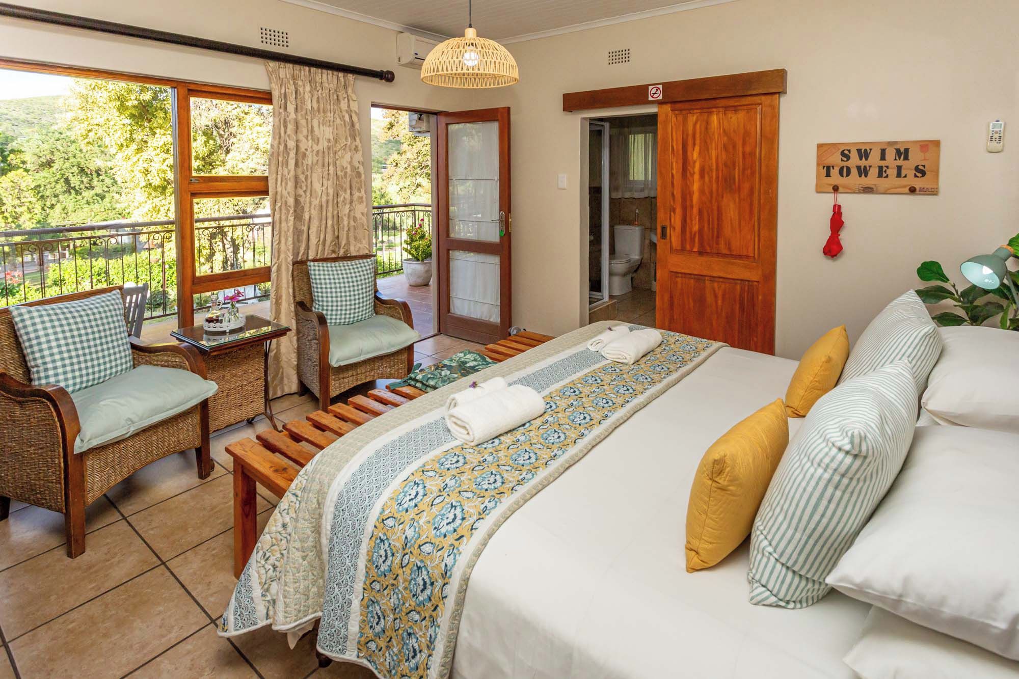Ein Schlafzimmer mit Bett, Stuhl, Tisch und Blick ins Freie.
