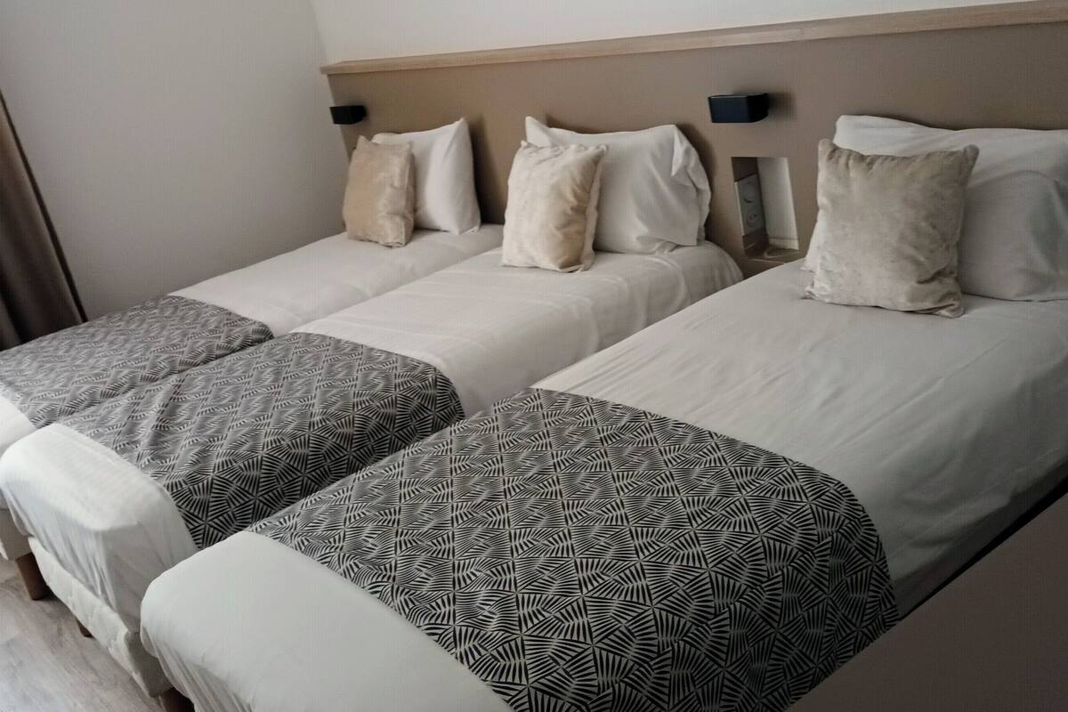 A hotel room with two beds, each with patterned bedspreads and matching pillows.