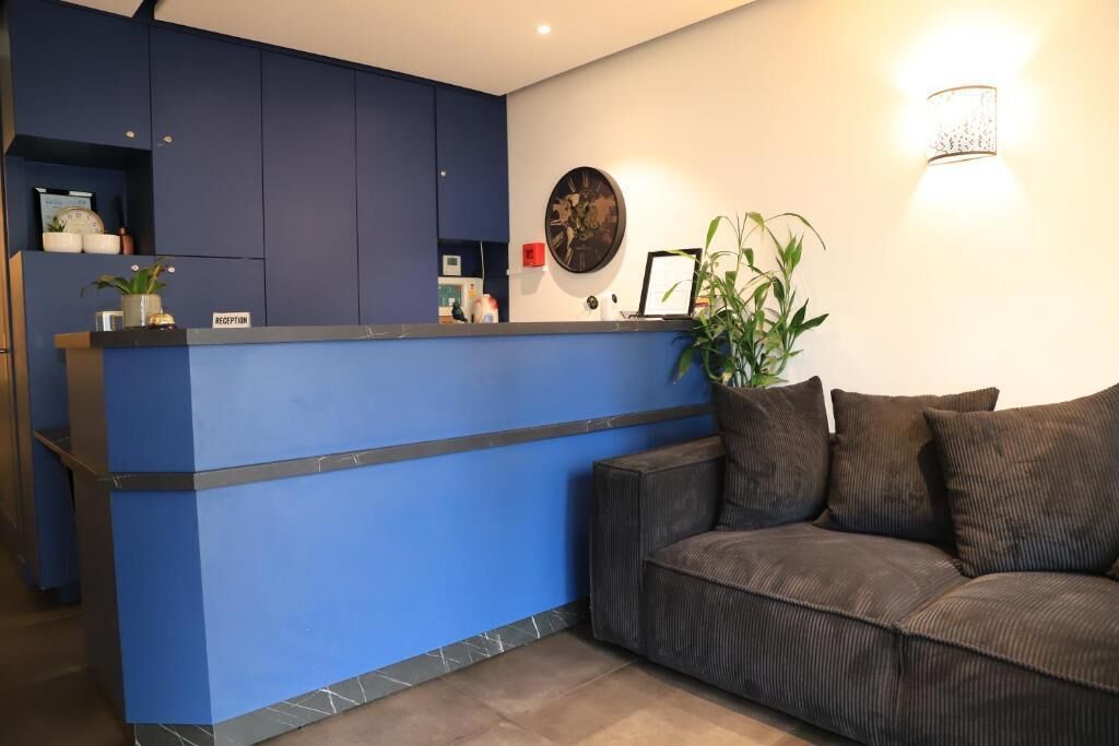 A reception area with a blue counter, a clock on the wall, and a sofa with cushions.
