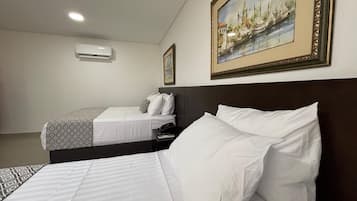 Une chambre d’hôtel avec deux lits, un tableau au mur et un appareil de climatisation.