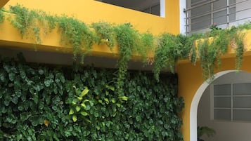 A yellow building with a green leafy wall and a tiled floor.