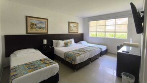 Une chambre d’hôtel avec deux lits, un bureau, une poubelle et un téléviseur fixé au mur.