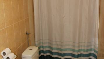 A bathroom with a toilet, a bidet, and a shower curtain.
