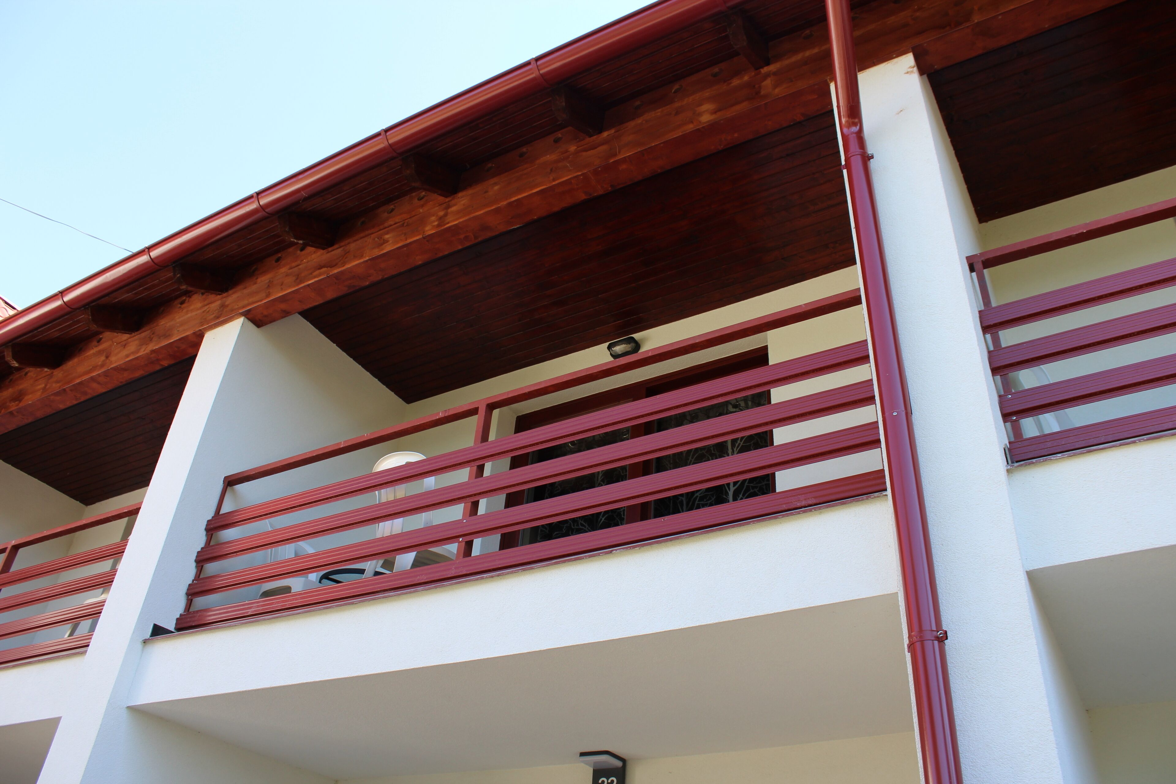 Un edificio de varios pisos con un balcón que tiene barandas rojas y techo de madera.