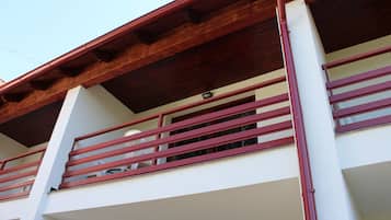Un edificio de varios pisos con un balcón que tiene barandas rojas y techo de madera.