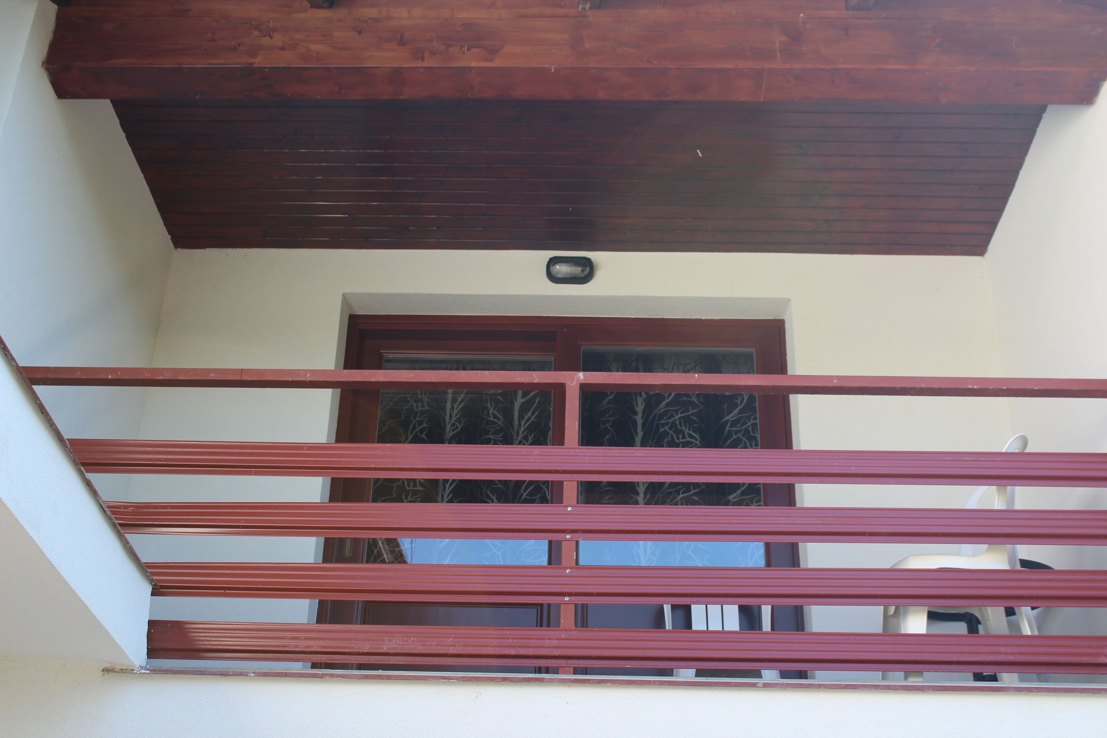 Un balcon doté d’un plafond en bois et d’une rambarde en métal.