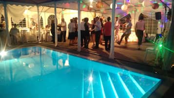 Un espace piscine doté d’une structure en forme de tente, de tables et de chaises.
