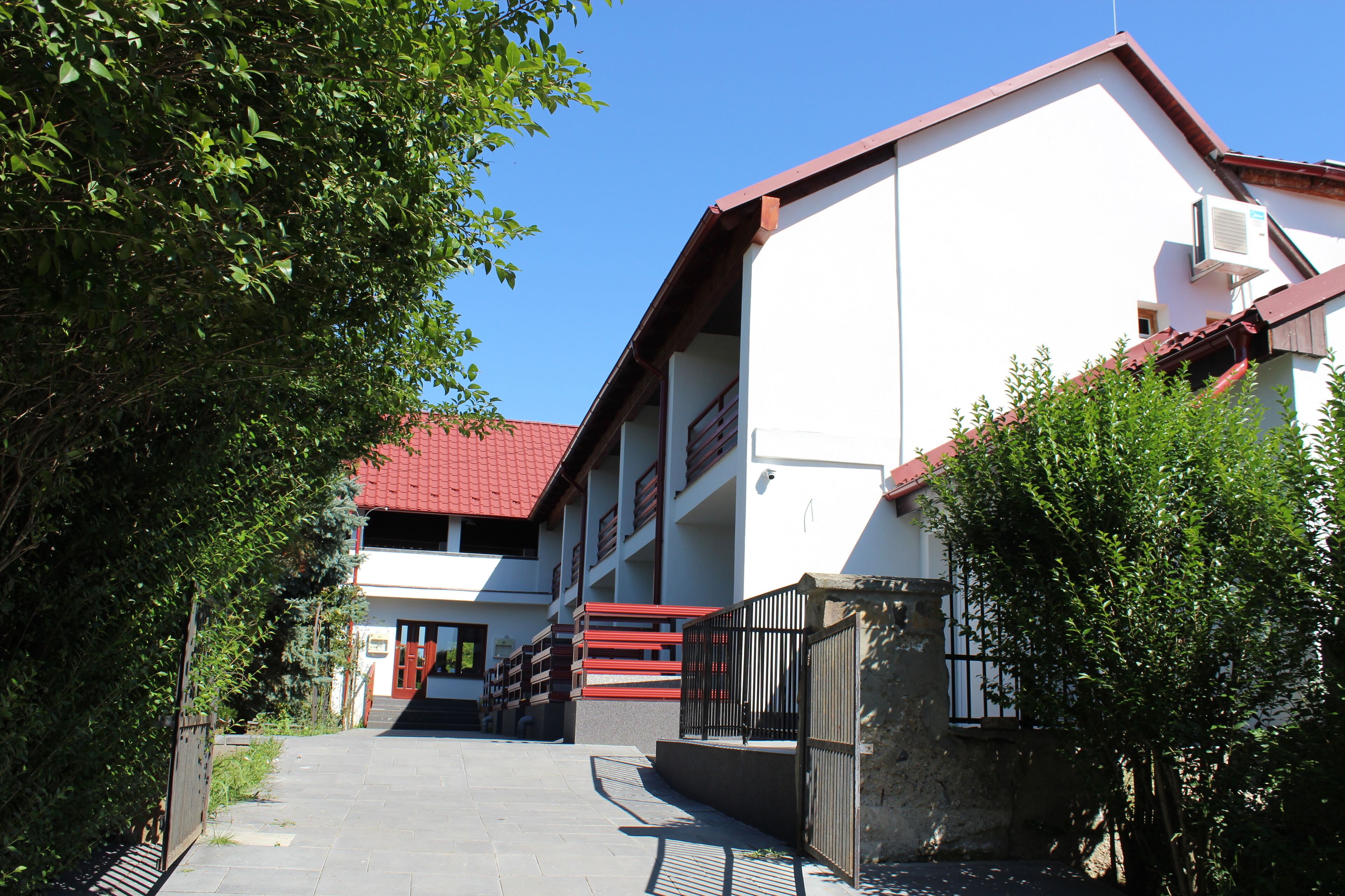 A building with a red roof, a staircase leading to a door, and a gated entrance.