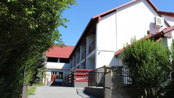 A building with a red roof, a staircase leading to a door, and a gated entrance.