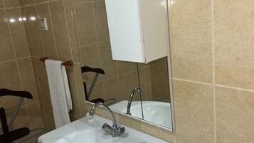 Un baño con lavamanos blanco, un espejo y un dispensador de papel higiénico.